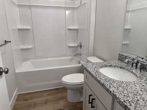 Bathroom with bathing tub / shower combination, dark wood-style floors, and vanity