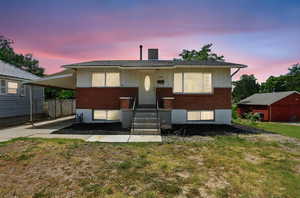 View of front of home with brick siding, a carport, a yard, and board and batten siding