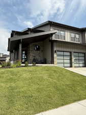 Contemporary home with stone siding, concrete driveway, a front lawn, and a garage