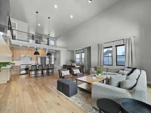 Living area featuring light wood finished floors, recessed lighting, and a towering ceiling