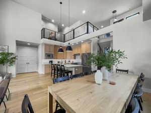 Dining space with light wood finished floors, a high ceiling, and recessed lighting