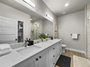 Full bathroom featuring double vanity, a shower stall, recessed lighting, and wood finished floors
