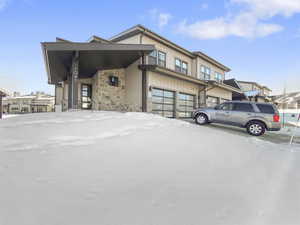 View of front facade featuring an attached garage and stone siding