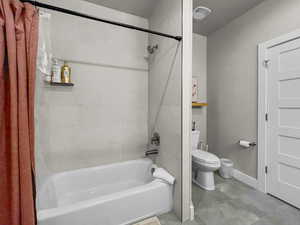 Full bathroom with shower / bathtub combination with curtain and toilet