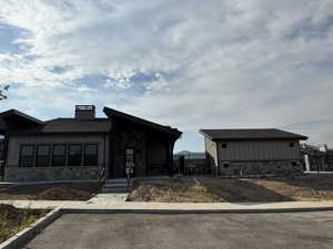 View of front of home featuring board and batten siding, stone siding, a shingled roof, and a chimney