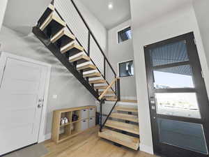 Entryway with stairway, wood finished floors, and a high ceiling