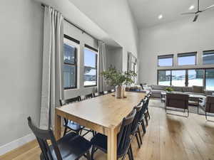 Dining space featuring light wood-style floors, ceiling fan, a high ceiling, and recessed lighting