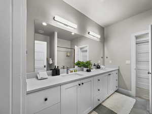 Bathroom featuring double vanity, concrete floors, and a shower