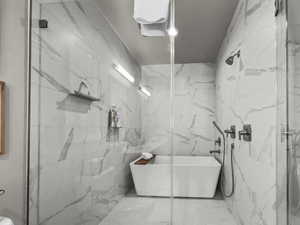 Bathroom featuring a marble finish shower, a soaking tub, and tile walls