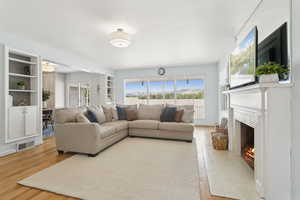 Living room featuring a lit fireplace, wood finished floors, and built in shelves