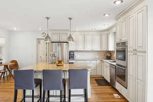 Kitchen featuring a breakfast bar area, appliances with stainless steel finishes, light wood-type flooring, a kitchen island, and light stone counters