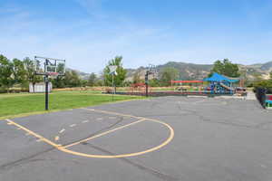 View of basketball court with a lawn, a mountain view, and a storage unit