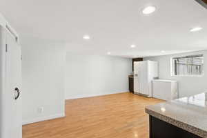 Kitchen with refrigerator, light wood-type flooring, recessed lighting, white refrigerator with ice dispenser, and white cabinets