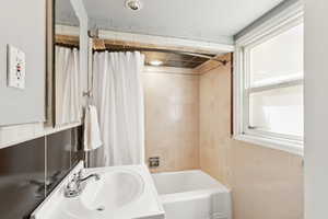 Full bathroom with shower / tub combo and tile walls