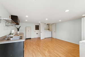 Kitchen with light wood-style floors, open shelves, recessed lighting, light countertops, and washer / dryer