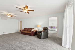 Living area with carpet floors and ceiling fan