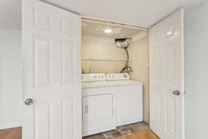Laundry area with washing machine and clothes dryer and wood finished floors