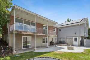 Back of house with an outdoor fire pit, a patio area, a lawn, brick siding, and stucco siding