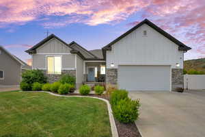 View of front of home with stone siding, board and batten siding, concrete driveway, and an attached garage