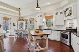 Kitchen with appliances with stainless steel finishes, a chandelier, dark wood-style floors, white cabinets, and recessed lighting