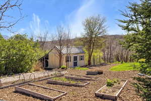 View of yard with a vegetable garden, an outbuilding, and a wooded view