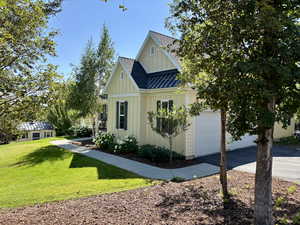 View of front facade with board and batten siding, driveway, a front yard, a shingled roof, and a garage