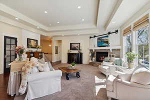 Living room with recessed lighting, a raised ceiling, and a stone fireplace
