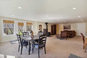 Dining space with a wood stove, light carpet, and recessed lighting