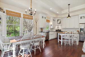 Dining room featuring dark wood finished floors, a chandelier, recessed lighting, and a raised ceiling