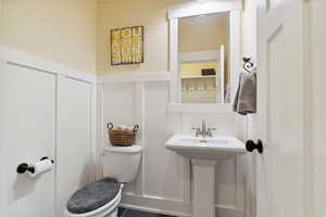 Half bathroom with a decorative wall and a wainscoted wall