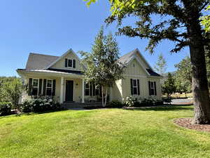 View of front facade featuring board and batten siding, a standing seam roof, a metal roof, a front lawn, and a porch