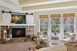Living room with a stone fireplace, a barn door, and carpet flooring