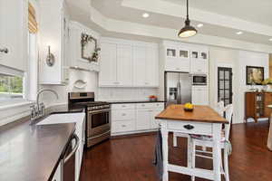 Kitchen with appliances with stainless steel finishes, dark wood-style flooring, white cabinets, recessed lighting, and pendant lighting