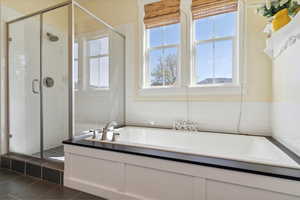 Bathroom with a stall shower, a garden tub, and tile patterned flooring