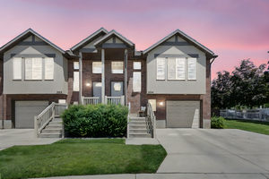 Bi-level home with a garage, brick siding, concrete driveway, stucco siding, and a lawn