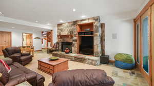 Living room featuring recessed lighting, stone finish floors, and a stone fireplace