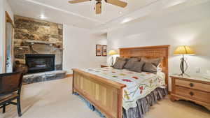 Bedroom featuring light colored carpet, a stone fireplace, recessed lighting, and a ceiling fan