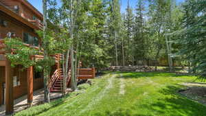 View of green lawn featuring a patio and a deck