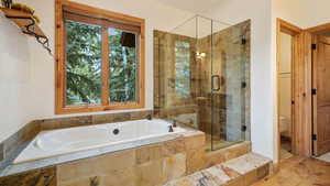 Bathroom featuring a bath, a shower stall, and wood finished floors