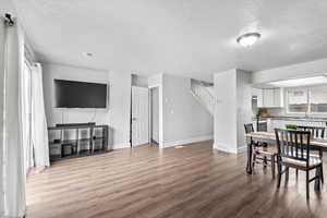 Dining area with a textured ceiling, wood finished floors, and stairs