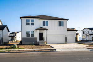 View of front of property featuring a shingled roof, driveway, board and batten siding, and an attached garage