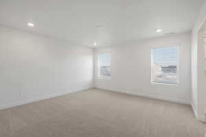 Empty room with light colored carpet and recessed lighting