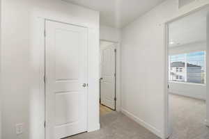 Hall featuring light colored carpet and baseboards