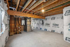 Unfinished basement with tankless water heater, heating unit, and electric panel
