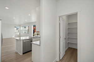 Kitchen featuring light wood-style floors, light stone countertops, stainless steel dishwasher, white cabinets, and recessed lighting