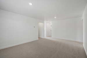 Empty room with light carpet and recessed lighting