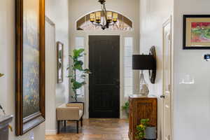 Foyer entrance featuring wood finished floors, a towering ceiling, and a chandelier