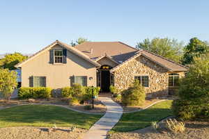 View of front of house with a front lawn, stucco siding, a tiled roof, and stone siding