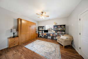 Sitting room featuring dark wood-type flooring, an office area, and a ceiling fan
