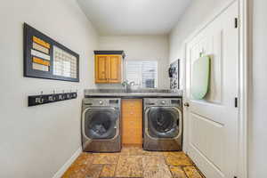 Laundry room featuring washing machine and clothes dryer, light stone finish flooring, and cabinet space